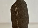 a black vase with a white line on it
