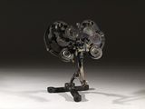 une sculpture représentant un ventilateur posé sur un trépied, sur une surface blanche