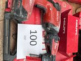 une perceuse sans fil rouge et deux autres outils posés par terre
