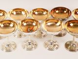nine wine glasses with gold rims on a white surface