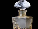 a bottle of perfume with a bust on top of it