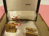 pair of gold cufflinks in a box on a pink surface
