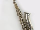 un saxophone argenté posé sur une surface blanche