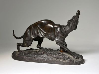 bronze statue of a dog running on a rock on a white background