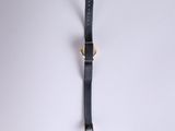 a black leather watch strap hanging on a white wall