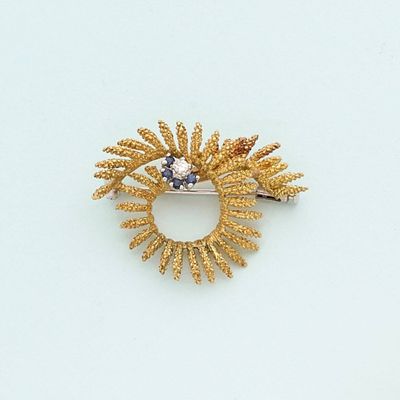 a gold brooch with a blue stone in it