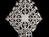 une image représentant une croix en argent posée sur un socle, sur fond noir