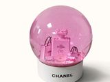 a pink snow globe with a chanel bag inside of it