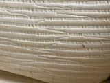 a close up picture of a white vase on a table