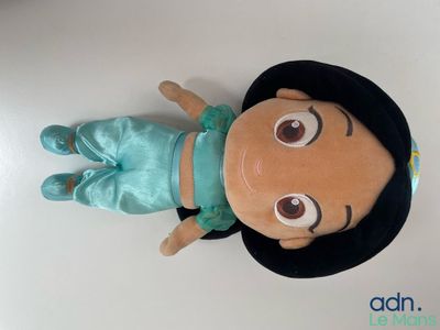a stuffed toy of a girl wearing a black hat and blue pants