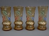 trois vases dorés ornés de motifs floraux sont alignés sur une surface grise