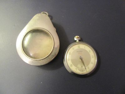 une montre de poche et une loupe posées sur une table