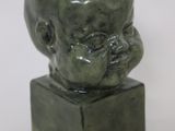 a green statue of a man with a head on a box