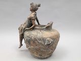 statue of a woman sitting on a vase with a book in her lap