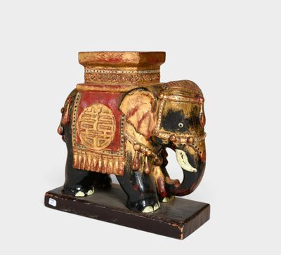 a wooden elephant with a red and gold decoration on it ' s back
