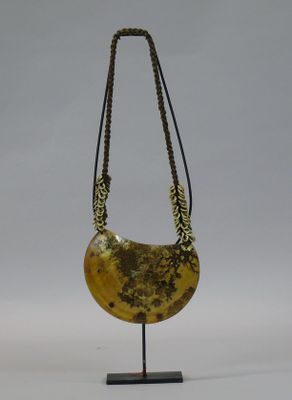 necklace made of yellow jade with gold leaf decoration on a black metal stand