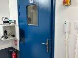une porte bleue dans une pièce où se trouve un téléphone accroché au mur