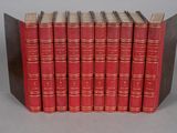 six red books lined up in a row on a gray surface