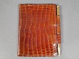 crocodile skin wallet with a gold clasp on a gray surface