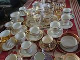 de nombreuses tasses et soucoupes posées sur une table recouverte d'une nappe rouge et blanche