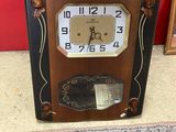 une horloge posée par terre devant un tableau