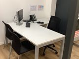 a white table with two black chairs and a computer on it