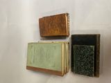 trois vieux livres posés sur une surface blanche, dont l'un n'a plus de couverture