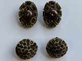 three antique buttons and a bead are sitting on a white surface