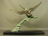 une sculpture en bronze représentant un oiseau perché sur une branche