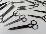 many pairs of scissors sitting on a white surface