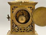 a gold clock with a bird on top of it