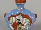 a small blue vase with a red top and a woman on it