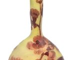 un vase jaune et marron orné de fleurs, posé sur une surface blanche