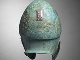 a close up of a bronze helmet on a gray background