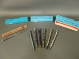 five pens and a box of pencils on a table