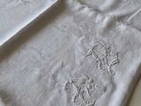 two white towels with embroidered designs on them on a bed