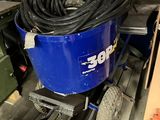 un seau bleu avec un tuyau posé sur un chariot dans un garage