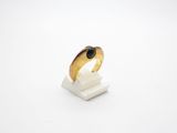 a gold ring with a black stone sits on a marble block