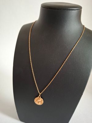 a gold necklace with a coin on a mannequin neck