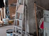 a ladder leaning against a wall next to a bucket of paint