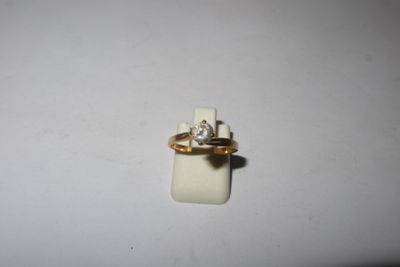 a gold ring with a diamond on it sitting on a white surface