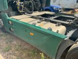 a green semi truck with a flat bed parked in the grass