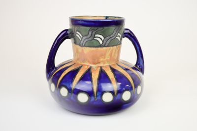 un vase bleu avec une anse jaune sur fond blanc