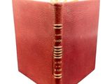 an old book with a red cover sitting on top of a table
