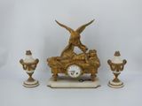 a clock with a bird on top of it next to three vases