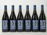 six bouteilles de vin rouge sont alignées sur une table