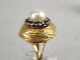 a gold ring with a pearl and blue stones on it