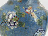 a blue vase with flowers on it sitting on a table