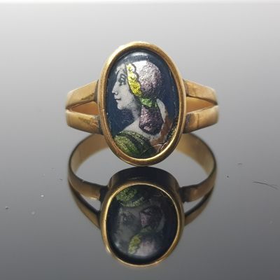 a close up of a gold ring with a picture of a woman on it