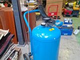 un réservoir bleu auquel est raccordé un tuyau, dans un garage
